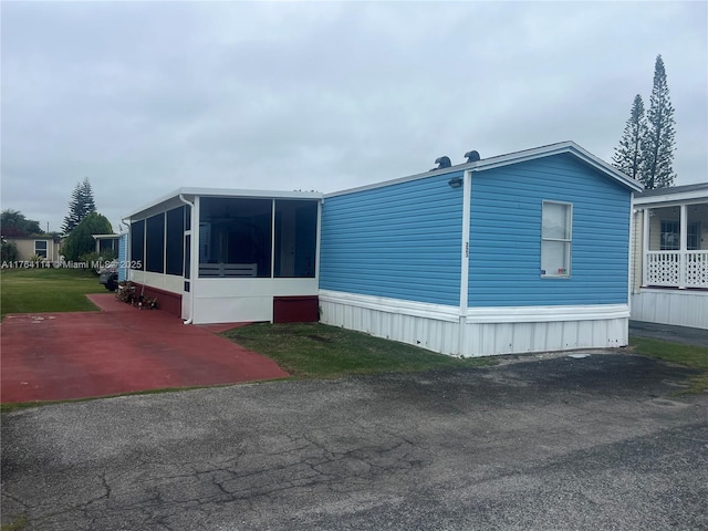 view of home's exterior with a yard and a sunroom