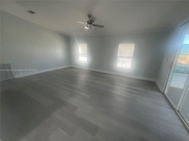 empty room featuring visible vents, baseboards, a ceiling fan, and wood finished floors