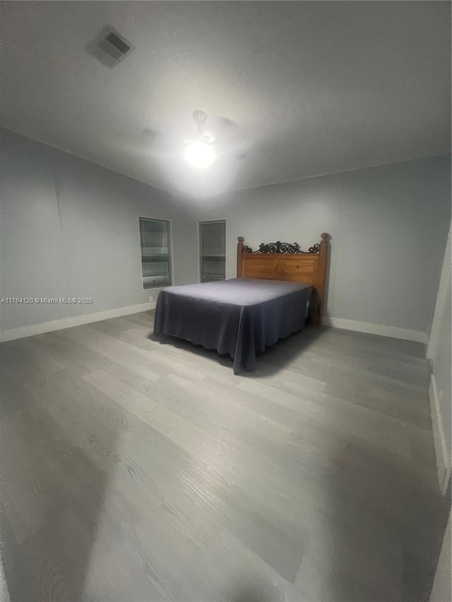 bedroom featuring wood finished floors, visible vents, and baseboards