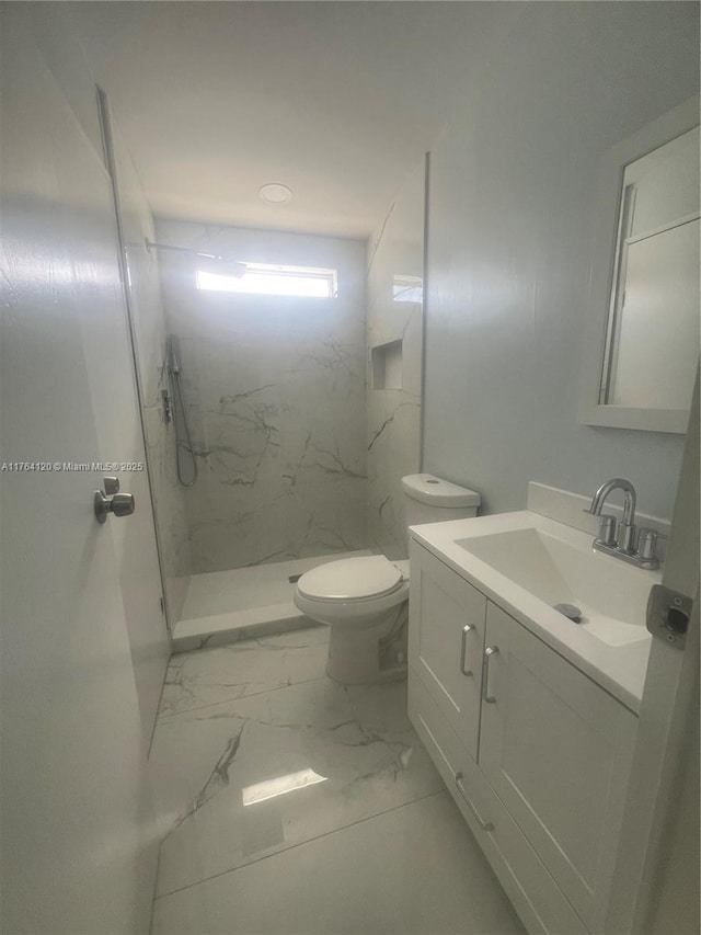 bathroom featuring a marble finish shower, toilet, marble finish floor, and vanity