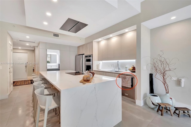 kitchen with visible vents, modern cabinets, a sink, a kitchen breakfast bar, and appliances with stainless steel finishes