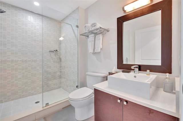 bathroom with a shower stall, toilet, and vanity