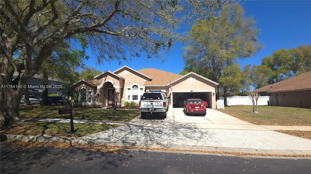 view of front of house with stucco siding, driveway, fence, a front yard, and an attached garage