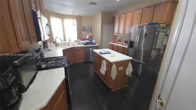 kitchen with a sink, light countertops, appliances with stainless steel finishes, and a center island