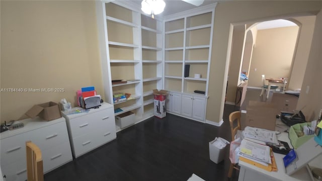 home office featuring arched walkways, dark wood-type flooring, and ceiling fan