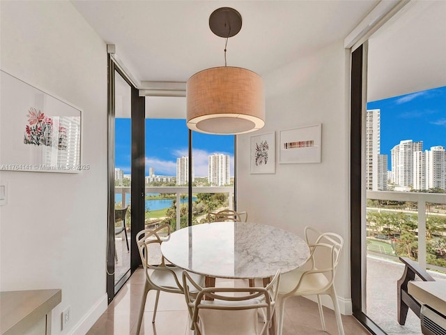 dining space with baseboards, a water view, a city view, expansive windows, and light tile patterned floors