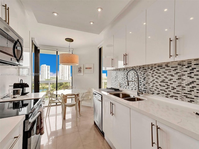 kitchen with tasteful backsplash, expansive windows, stainless steel appliances, white cabinetry, and a sink