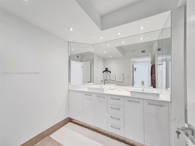 bathroom featuring double vanity, recessed lighting, baseboards, and a sink