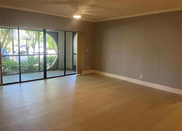 empty room with crown molding, wood finished floors, baseboards, and ceiling fan