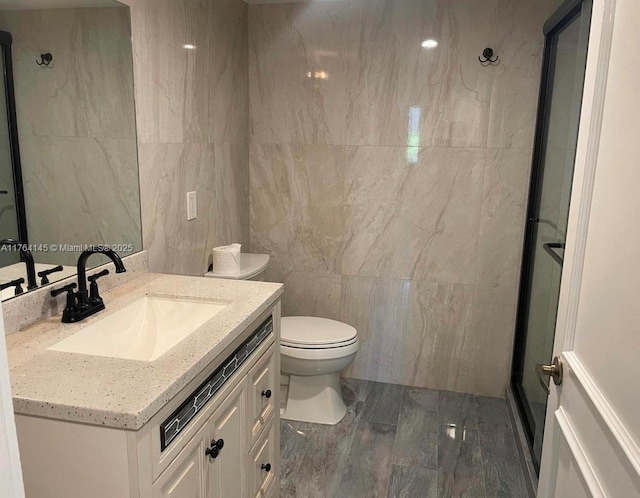 bathroom featuring vanity, tile walls, a shower stall, and toilet