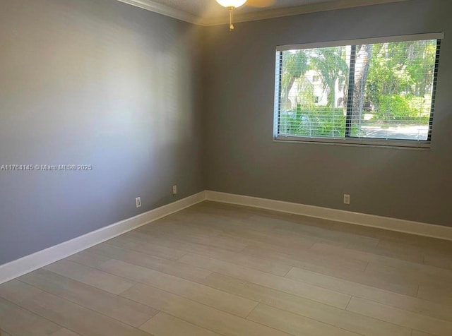 spare room with ceiling fan, light wood-style floors, baseboards, and ornamental molding