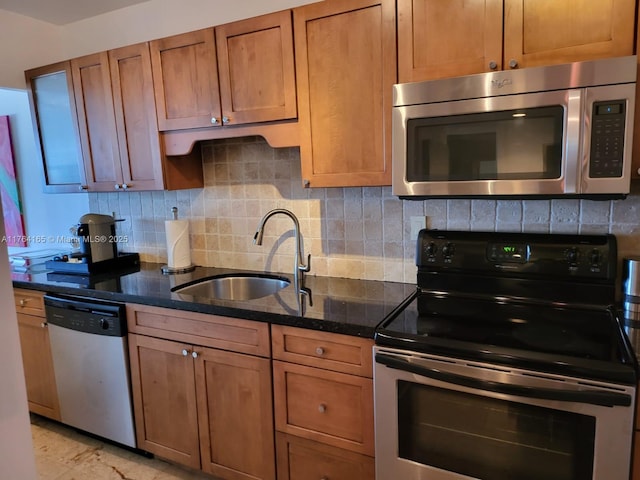 kitchen with a sink, dark stone counters, backsplash, and stainless steel appliances