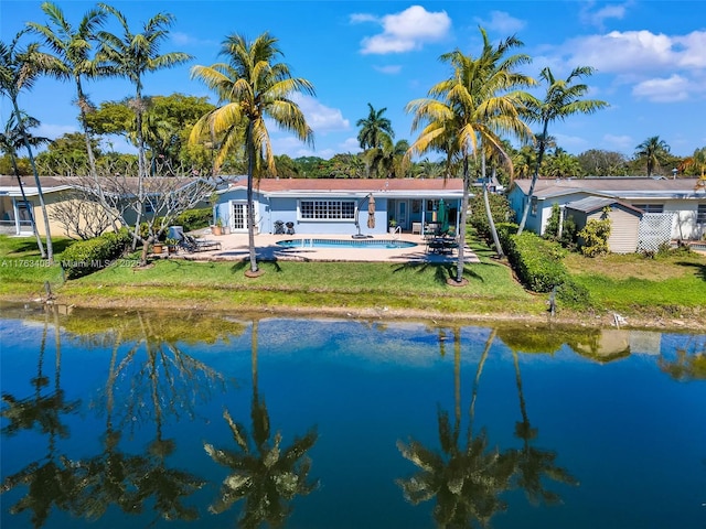 rear view of house with a patio area, a yard, an outdoor pool, and a water view