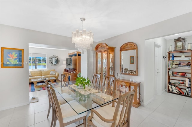 dining space with a chandelier, light tile patterned floors, and baseboards