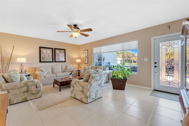 living area with light tile patterned flooring, baseboards, and ceiling fan