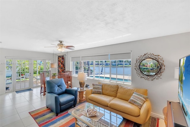 living room with ceiling fan, light tile patterned floors, french doors, and a textured ceiling