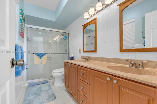 bathroom with a sink, double vanity, a shower stall, and tile patterned flooring