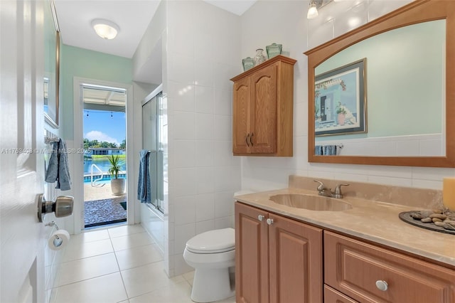 bathroom featuring vanity, a stall shower, tile patterned flooring, tile walls, and toilet