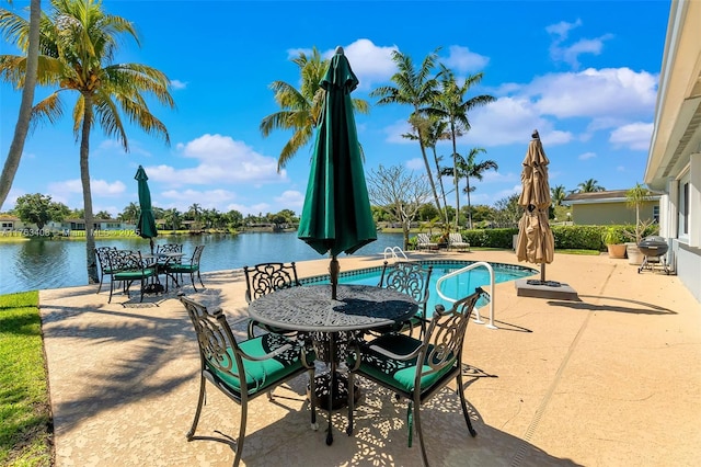 view of patio with grilling area, an outdoor pool, and a water view