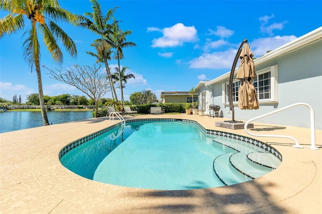 outdoor pool featuring a water view and a patio area