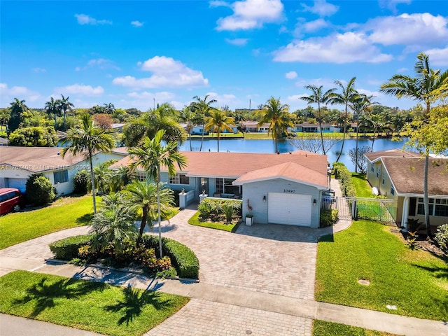 ranch-style home featuring a water view, a gate, decorative driveway, fence, and a front yard