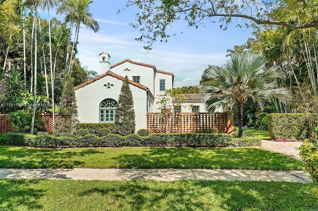 view of front of property with a front yard, a tiled roof, and stucco siding