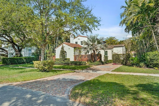 mediterranean / spanish house featuring a front lawn, a tiled roof, and stucco siding