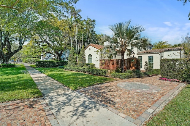 exterior space with stucco siding, a front lawn, and a tiled roof