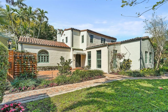 mediterranean / spanish-style house featuring a front lawn, a tiled roof, and stucco siding