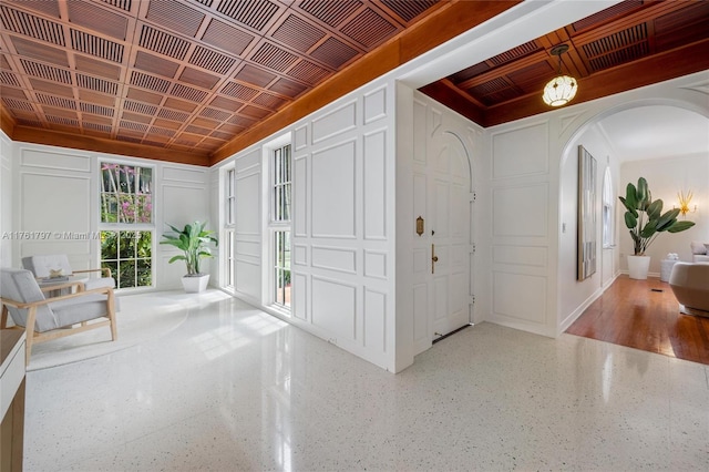 foyer with a decorative wall, arched walkways, and speckled floor