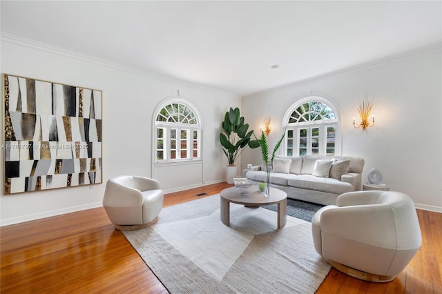 living room with baseboards, plenty of natural light, wood finished floors, and crown molding