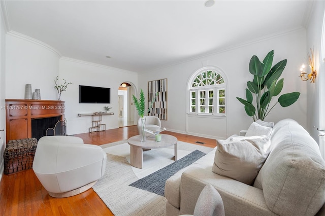 living room with light wood finished floors, baseboards, and ornamental molding