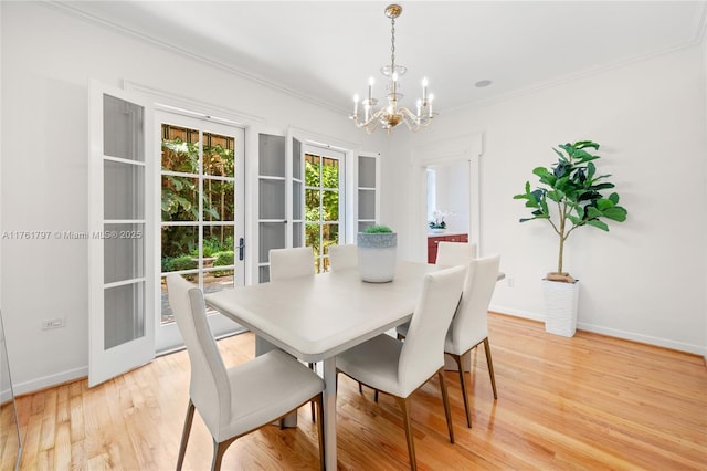 dining area with crown molding, a notable chandelier, light wood-style floors, and baseboards