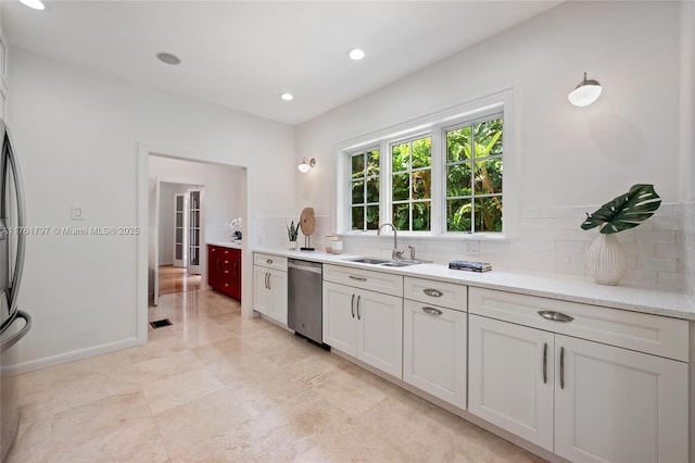 kitchen featuring visible vents, a sink, backsplash, light countertops, and dishwasher