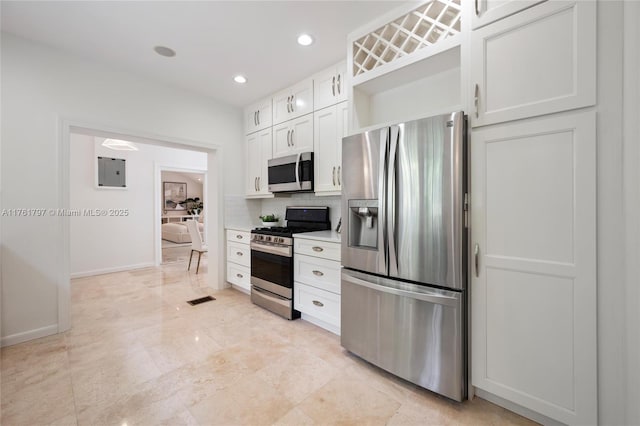 kitchen with white cabinetry, stainless steel appliances, light countertops, decorative backsplash, and baseboards