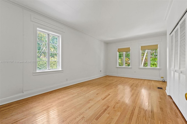 unfurnished bedroom featuring baseboards, multiple windows, and light wood finished floors