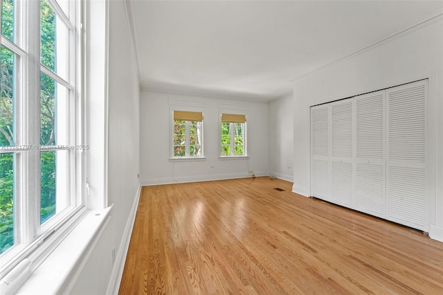 unfurnished bedroom featuring baseboards, light wood-style flooring, and crown molding