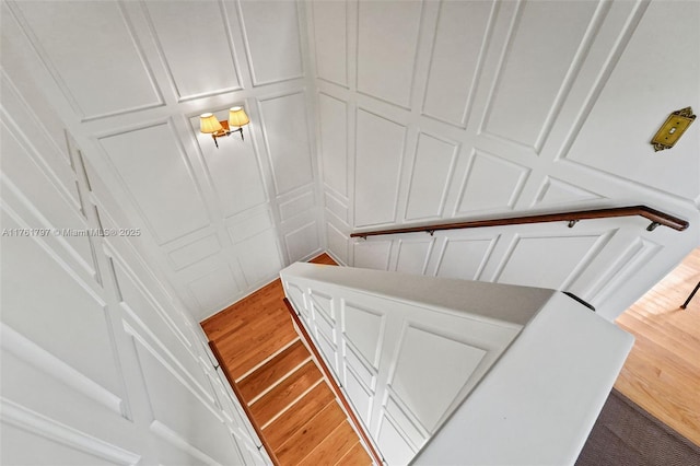 stairway featuring a decorative wall and wood finished floors