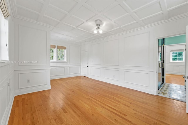 unfurnished room with a decorative wall, plenty of natural light, and light wood-style floors