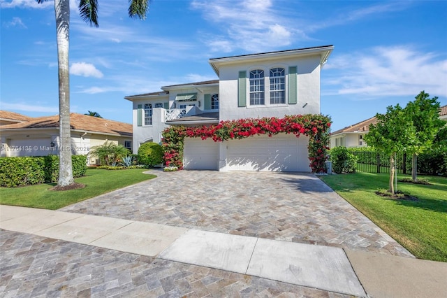 view of front facade with a front lawn, decorative driveway, a garage, and stucco siding