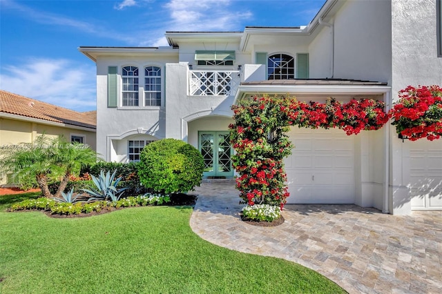 view of front facade with stucco siding, decorative driveway, a garage, and a front lawn