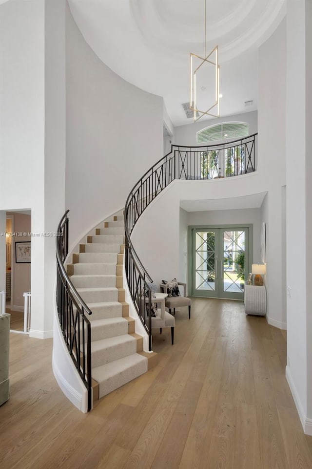 stairway with a chandelier, a raised ceiling, baseboards, and hardwood / wood-style flooring