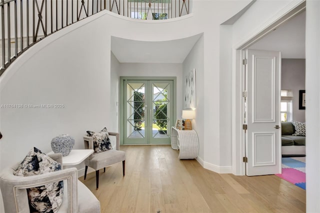 foyer with light wood finished floors, a healthy amount of sunlight, french doors, and baseboards