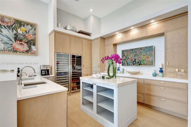 kitchen featuring open shelves, light brown cabinetry, a sink, light countertops, and light wood-type flooring