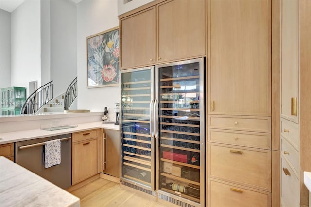 kitchen featuring light brown cabinets, dishwasher, light countertops, and light wood-style floors