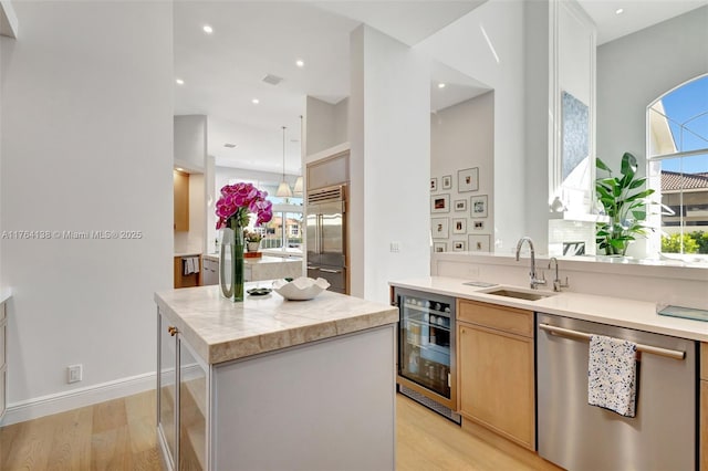 kitchen featuring a center island, wine cooler, light countertops, appliances with stainless steel finishes, and a sink