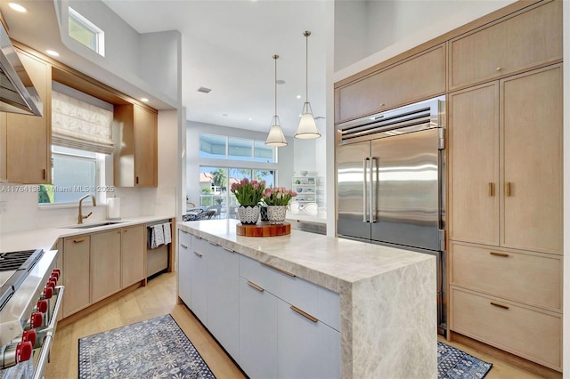 kitchen with light wood-style flooring, light brown cabinets, a sink, a center island, and high end appliances