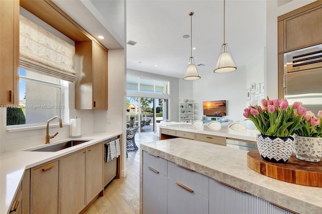 kitchen featuring visible vents, a sink, light countertops, light wood-style floors, and stainless steel dishwasher