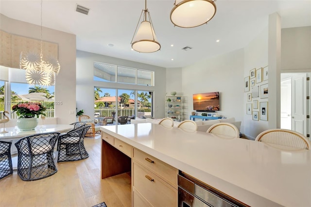 kitchen featuring visible vents, decorative light fixtures, light wood-style floors, and open floor plan