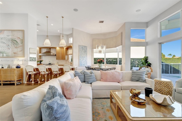 living room featuring recessed lighting, visible vents, light wood-style flooring, and a high ceiling